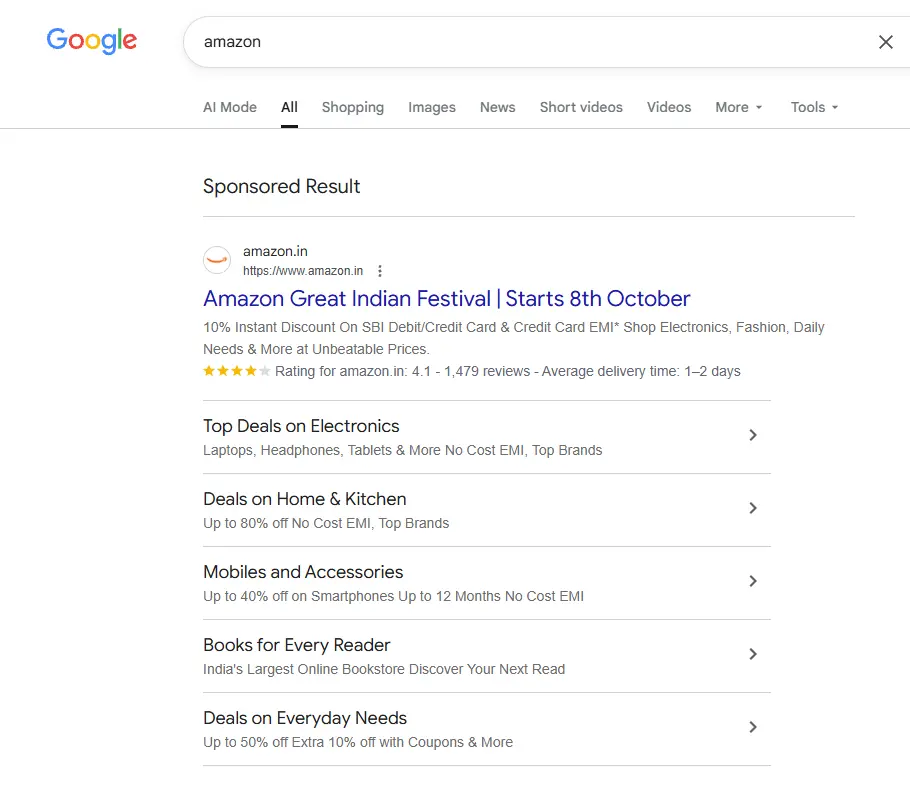 Google search results for Amazon Great Indian Festival 2026, showing a sponsored Amazon.in result with the headline “Amazon Great Indian Festival | Starts 8th October” and promotional messaging for discounts on electronics, fashion, daily needs, home and kitchen products, mobiles and accessories, books, and everyday essentials. The search result includes category-specific deal links such as electronics, home and kitchen, mobiles and accessories, books, and everyday needs, illustrating how Amazon promotes its festive shopping event directly within Google Search. Amazon’s current business page also states that the Great Indian Festival starts 8 October 2026.