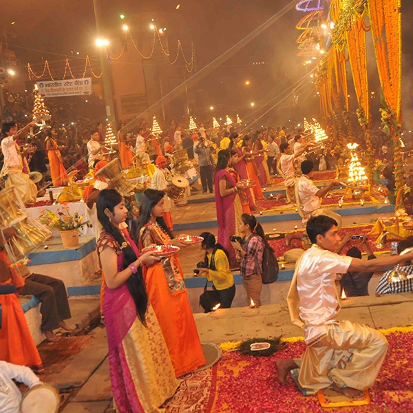 Dev Deepawali celebration at Varanasi ghats showing devotees performing Ganga Aarti with lit diyas, traditional attire, and vibrant decorations