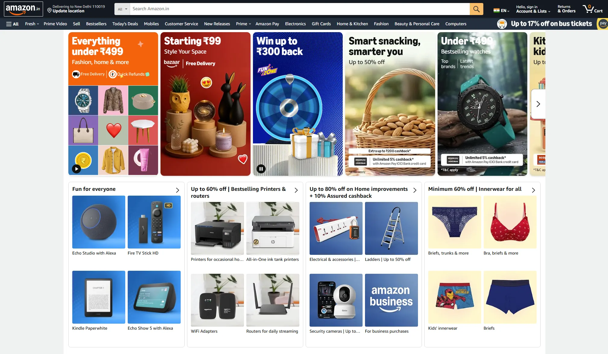 Screenshot of the Amazon India homepage, showcasing a vast and diverse online marketplace interface. The top navigation bar features the Amazon logo, location updater, a global search bar with category filters, language selection, sign-in options for existing accounts, order tracking, and a shopping cart icon. Below the main navigation, prominent quick-links include Fresh for groceries, Prime Video for streaming, Bestsellers, Today's Deals, Mobiles, Customer Service, New Releases, Amazon Pay, Electronics, Gift Cards, Home & Kitchen, Fashion, Beauty & Personal Care, and Computers. The page highlights multiple promotional banners: an offer for up to 17% off on bus tickets, 'Everything Starting 99', a 'Kit under 7499' for smart snacking, and 'Style Your Space' bazaar. Additional deals include up to 50% off on top brands, latest trends, and kid's products. Financial offers are prominently displayed, such as extra up to ₹200 cashback and unlimited 5% cashback with the Amazon Pay ICICI Bank credit card. Product category promotions feature up to 60% off on bestselling printers and routers, up to 80% off on home improvements, and minimum 60% off on innerwear for all. Electronic devices like Echo Studio with Alexa, Fire TV Stick HD, Kindle Paperwhite, Echo Show 5, WiFi adapters, routers, and security cameras are also advertised. The page also includes a section for Amazon Business and kids' innerwear, creating a comprehensive snapshot of Amazon India's extensive product offerings and seasonal deals.
