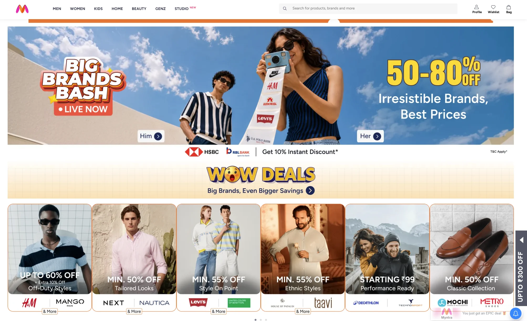 Myntra ecommerce fashion website homepage showing a large Big Brands Bash promotional banner with a live sale announcement and discounts of 50–80% off on popular fashion and lifestyle brands. The top navigation bar includes categories for Men, Women, Kids, Home, Beauty, GenZ, and Studio, along with a search bar and Profile, Wishlist, and Bag options. The main hero banner features male and female fashion models against a bright blue sky and promotes discounted branded fashion with separate shopping options for men and women. A promotional strip below the banner highlights an additional 10% instant discount through HSBC and RBL Bank. The page also includes a Wow Deals section promoting bigger savings, followed by multiple brand-specific promotional cards featuring H&M and Mango Man, Next and Nautica, Levi’s and United Colors of Benetton, House of Pataudi and Taavi, Decathlon and Technosport, and Mochi and Metro. Each card highlights different discounts and offers on clothing, footwear, accessories, and lifestyle products, demonstrating Myntra’s use of homepage banners, brand promotions, discount messaging, and visually engaging ecommerce marketing campaigns.